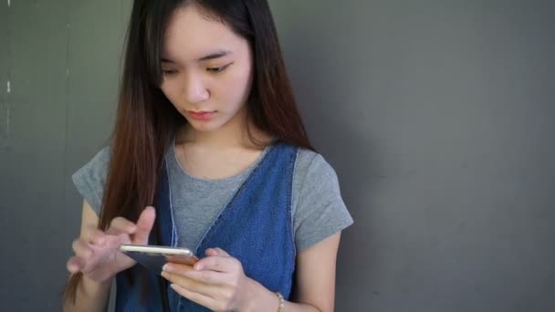 若いアジア中国の女性は、スマート フォンを使用してお楽しみください。 — ストック動画
