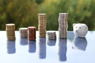 coins stack of EU cash and piggy bank on a blurred background landscape, business concept clipart