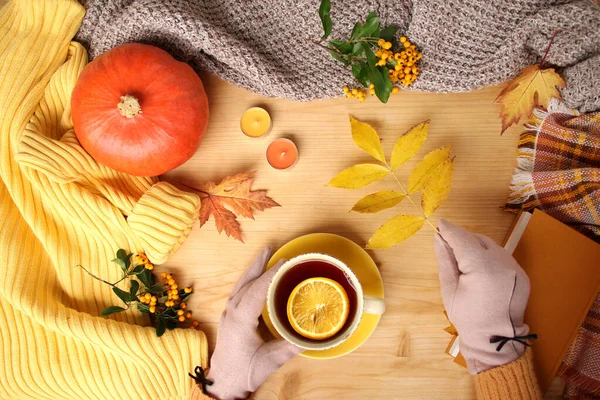 Frauenhände mit einer Tasse heißem Tee, Herbst flach im skandinavischen Hugg-Stil, mit gelben Blättern, kuscheliger Strickware, Kürbis und Beeren — Stockfoto