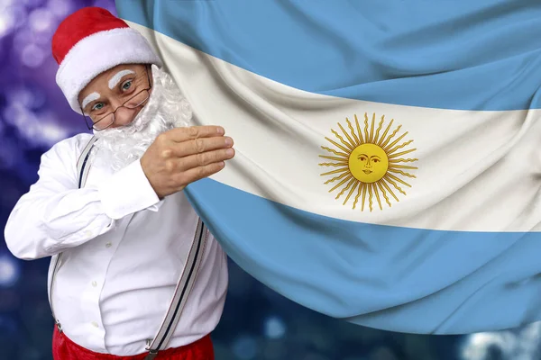 Santa Claus con barba sostiene una hermosa bandera nacional de color del estado de Argentina sobre tela, concepto de turismo, Año Nuevo 2020 y Navidad, perspectivas económicas y políticas — Foto de Stock