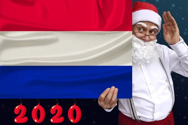 Père Noël avec une barbe tient un beau drapeau national coloré de l'État des Pays-Bas sur le tissu, concept de tourisme, Nouvel An et Noël, perspectives économiques et politiques — Photo