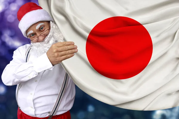 Santa Claus s plnovousem drží krásnou barevnou národní vlajku Japonska na tkaniny, koncept cestovního ruchu, Nový rok a Vánoce, ekonomické a politické vyhlídky — Stock fotografie