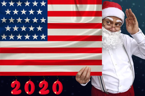 Santa Claus med skägg innehar en vacker färgad nationell flagga i delstaten USA på tyg, begreppet turism, nytt år och jul, ekonomiska och politiska utsikter — Stockfoto