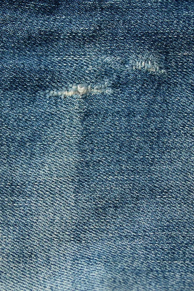 穴、古いジーンズの穴、青いデニム織り、テクスチャ、クローズアップ、コピースペース — ストック写真