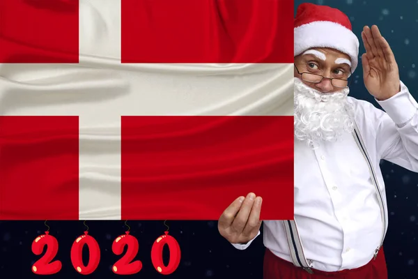 Sakallı Noel Baba, modern Danimarka devletinin renkli ulusal bayrağının 2020 yılına ait güzel bir fotoğrafını taşıyor. Turizm, yeni yıl, ekonomik ve politik profesyoneller. — Stok fotoğraf