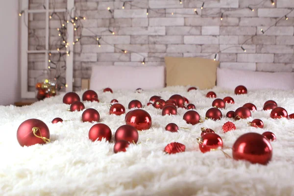 다양 한 크기의 아름다운 붉은 크리스마스 트리 공 이 침대의 큰 침대 위에 널브러져 있고, 휴일 조명 벽에 있으며, 크리스마스와 새해의 개념, 아늑 한 H — 스톡 사진