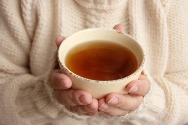 Bir kadının elinde bir fincan sıcak kokulu çay örgü süveter dokusu, yakın çekim, fotokopi alanı, sonbahar havası.