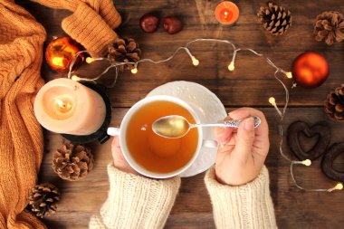 Sıcak örülmüş kazaklı kadın elinde bir fincan çay, limon ve portakal, mumlar, kağıt bir hediye, üst manzara, Noel ve yeni yıl konsepti, rahat bir ev