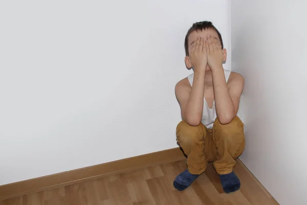 Kırgın çocuk köşede oturuyor, utancından yüzü elleriyle kapanıyor, pedagojik bir kavram. — Stok fotoğraf