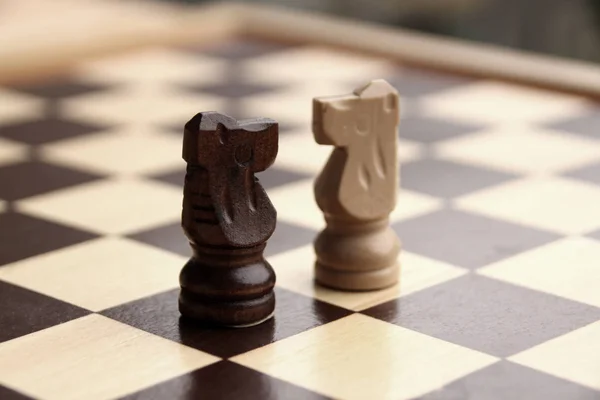 Pezzi di legno, cavalli a scacchi, bianco e marrone scuro su una scacchiera, concetto di gioco — Foto Stock