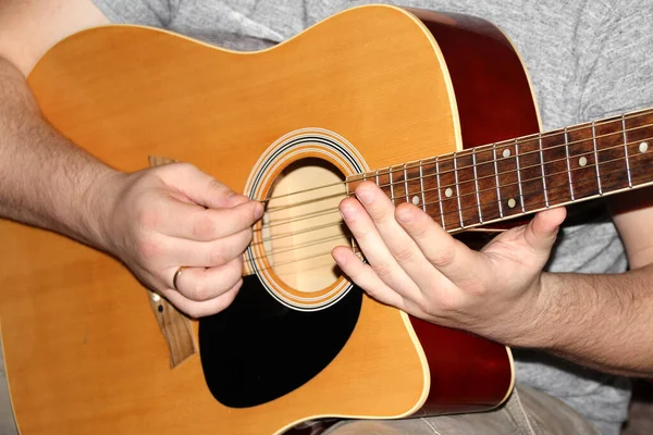 Homem toca uma guitarra de madeira de seis cordas, conceito musical, close-up — Fotografia de Stock
