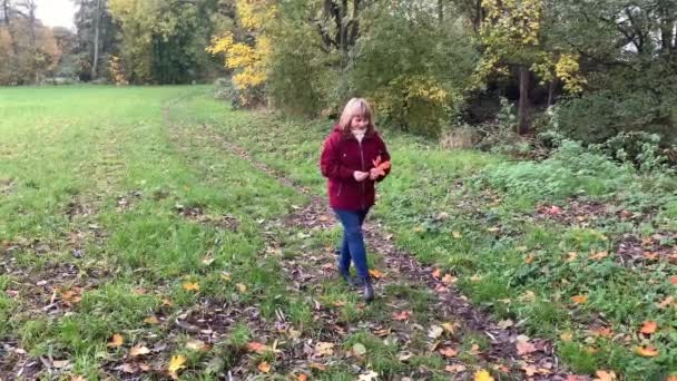 청바지를 중년의 과부르군 재킷을 가을에 공원에서 노랗고 오렌지색 기분좋은 분위기를 — 비디오
