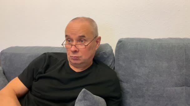Μεσήλικας Φαλακρός Γυαλιά Κάθεται Στον Καναπέ Βλέπει Τηλεόραση Ενθουσιασμό Κοντινό — Αρχείο Βίντεο