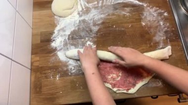 Kadın ahşap bir masada et ve hamur hazırlıyor, un serpilmiş, yemek pişirme konsepti.