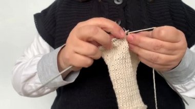 Siyah yelekli kadın elleriyle doğal yünden yapılmış örgü iğneleri örüyor, hobi olarak, örgü örüyor, örgü örüyor.
