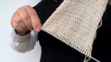 Siyah yelekli kadın elleriyle doğal yünden yapılmış örgü iğneleri örüyor, hobi olarak, örgü örüyor, örgü örüyor.