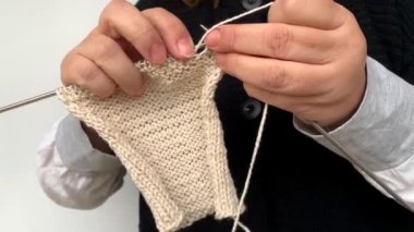 Siyah yelekli kadın elleriyle doğal yünden yapılmış örgü iğneleri örüyor, hobi olarak, örgü örüyor, örgü örüyor.