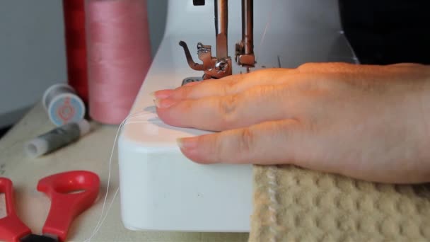 femme coud tissu texture sur une machine à coudre moderne tout en étant assis à la maison sur un canapé gris, concept de passe-temps et d'aiguille, gros plan 