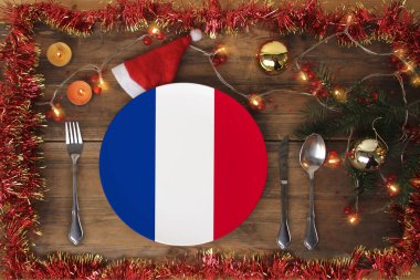Fransız bayrağıyla servis edilen güzel bir Noel kompozisyonu çatal bıçak, süs, çelenk, ladin dalı, mum, geleneksel Noel yemeği konsepti, gastronomik turizm ile servis ediliyor.