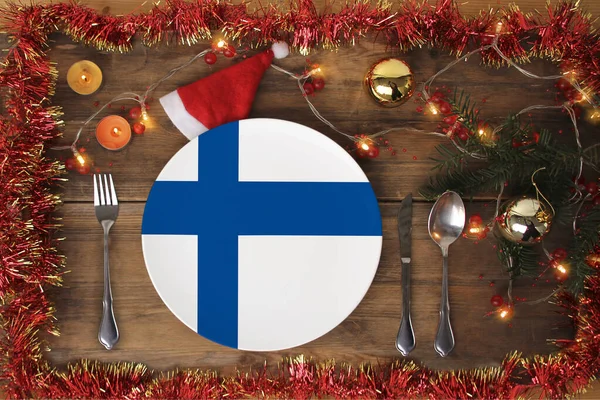 Vacker julsammansättning med en tallrik med Finlands nationalflagga, juldekorationer, kransar, ljus, begreppet traditionell nyårsmat, gastronomisk turism — Stockfoto