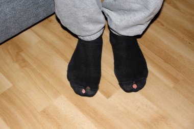 partial photograph of a man's legs in black holey socks rubbed on his fingers clipart