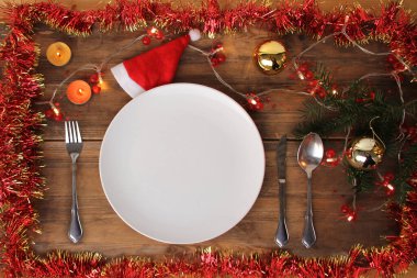 Eski bir ahşap masa, süs, çelenk, Noel ağacı dalı, mumlar, Noel yemeği, Noel konsepti üzerinde güzel bir Noel kompozisyonu içinde çatal bıçak takımı servis edilir.