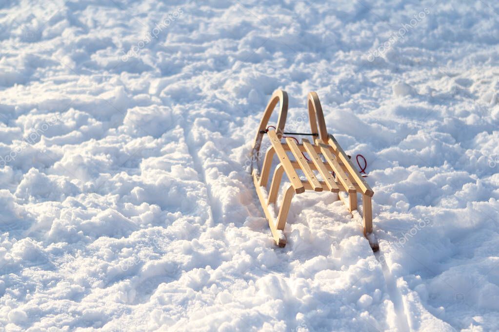 lonely wooden sled standing in the snow against the backdrop of a beautiful winter landscape with white snowy trees in the park, deep tracks in the snow, the concept of seasonal outdoor activities