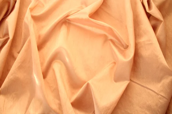 Beautiful silk fabric of delicate doggie color, light orange, draped with small folds, softly flowing, luxurious, wedding concept, texture, background, card form, copy space — Stock Photo, Image