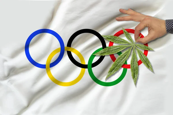 Bild des grünen Cannabisblattes auf der schönen olympischen Fahne, Konzept des medizinischen Cannabis, Doping-Testkonzept, medizinische Untersuchung — Stockfoto