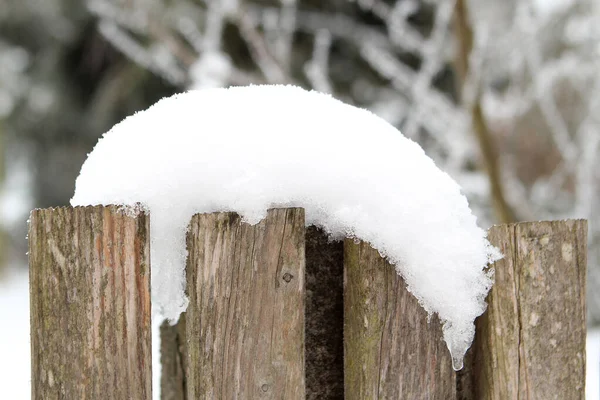 Alter Holzzaun, bedeckt mit einer weißen Schneewehe auf winterlichem Hintergrund, saisonal, Wetter, erstes Schneefallkonzept, horizontal, Nahaufnahme — Stockfoto