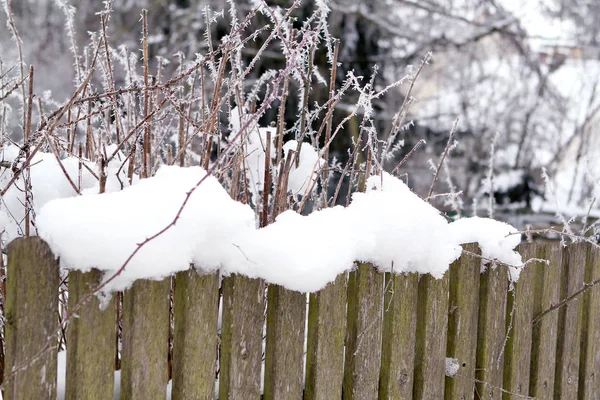 Παλιός ξύλινος φράχτης καλυμμένος με λευκό χιόνι σε χειμερινό φόντο, εποχικός, καιρός, έννοια της πρώτης χιονιού, οριζόντιος, κοντινό πλάνο — Φωτογραφία Αρχείου