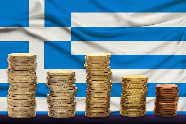 Стопки монет евро на фоне шелкового флага Греции, концепции финансового роста, динамики национальной валюты, финансовой девальвации, инфляции — стоковое фото