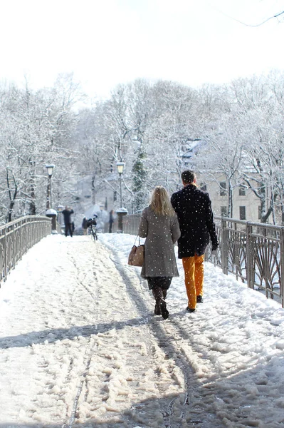 Hombre y mujer caminan juntos por el puente entre el frío paisaje blanco de la ciudad de Munich en la nieve, un parque en invierno, el concepto de amor, un matrimonio feliz — Foto de Stock