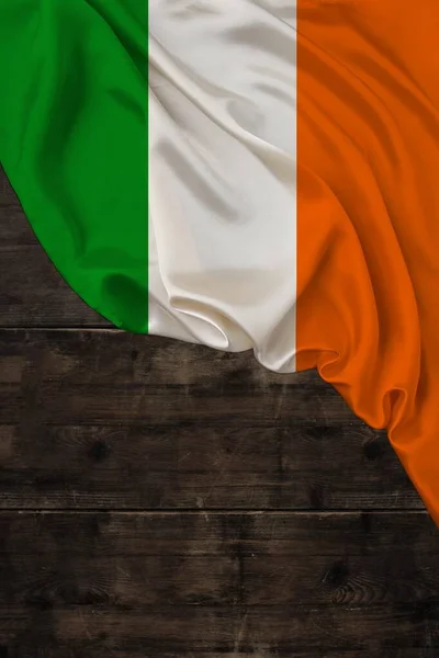 Bandera nacional de color vertical del estado moderno de Irlanda, hermosa seda, fondo madera vieja, concepto de turismo, economía, política, emigración, día de la independencia, espacio de copia, plantilla —  Fotos de Stock