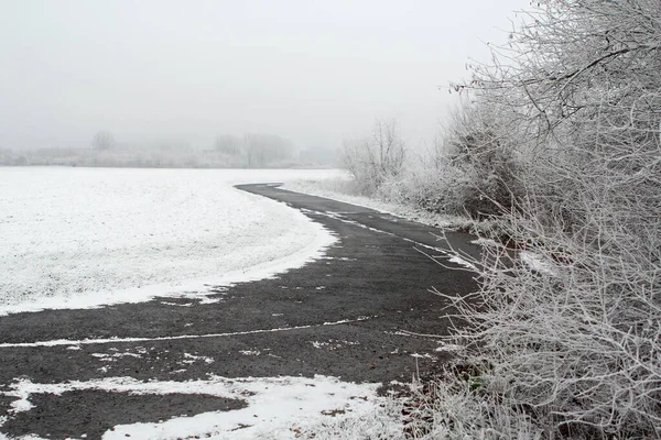 Снегопад и заснеженная дорога сельской дороги, концепция коммунальных услуг, сезонные изменения в природе, снегопады, погода, климат — стоковое фото