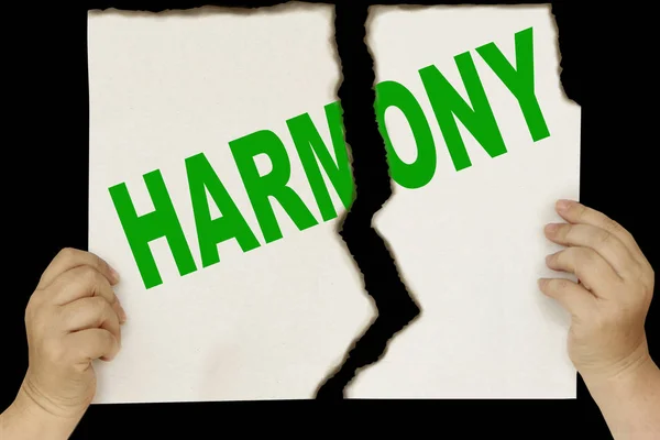 Kobiece ręce trzymać na czarnym tle arkusz tektury rozdarty w dwóch ze słowem Harmony — Zdjęcie stockowe