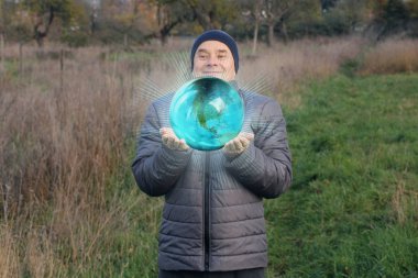 Gülümseyen şapkalı yaşlı pozitif adam ellerini önde tutuyor. 