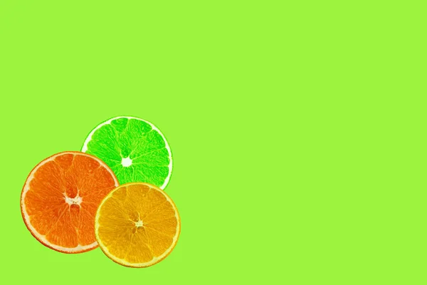 Ensemble avec des tranches juteuses d'orange, citron, citron vert sur un fond vert pour un menu ou une recette, le concept de végétarien, vitamine et aliments sains, fond, motif pour le textile, papier peint, espace de copie — Photo