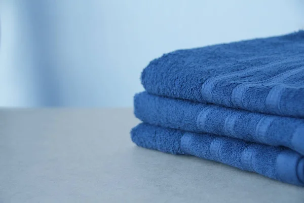 Куча чистых махровых хлопчатобумажных голубых полотенец, крупным планом, на светлом фоне, копировальное пространство, концепция чистоты, процедура ванны, спа — стоковое фото