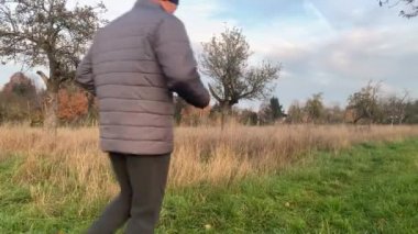 Ceketli orta yaşlı bir adam kışın ya da sonbaharda parkta koşar. Spor, uzun yaşam ve sağlıklı bir yaşam tarzı.