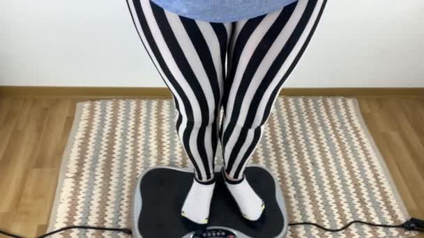 縞模様のレギンスの女性は振動シミュレータ上で物理的な演習を行います スポーツの概念 身体活動 健康的なライフスタイル — ストック動画