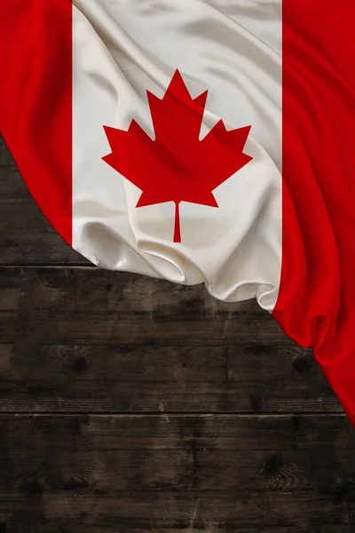 Vertikal färgad nationell flagga av moderna staten Kanada, vackra silke, gammalt trä bakgrund, begreppet turism, ekonomi, politik, emigration, självständighetsdagen, kopiera utrymme, mall — Stockfoto
