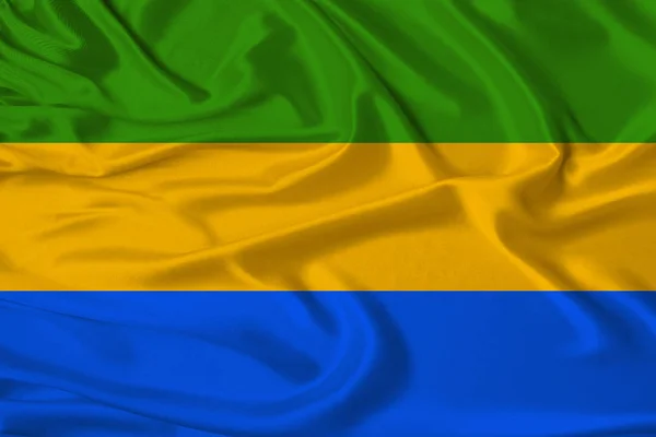 Beautiful photo of the national flag of Gabon on delicate shiny silk with soft draperies, the concept of state power, country life, horizontal, close-up, copy space — Stock Photo, Image