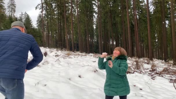 穿着夹克的中年妇女和男子在冬季漫步于白雪密布的森林中 玩耍着雪球 享受着运动的理念 健康的生活方式 — 图库视频影像