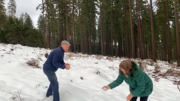 穿着夹克的中年妇女和男子在冬季漫步于白雪密布的森林中 玩耍着雪球 享受着运动的理念 健康的生活方式 — 图库视频影像