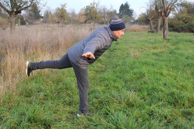 Gülümseyen şapkalı yaşlı adam spora gider, doğada denge için fiziksel egzersizler yapar, sağlıklı yaşam tarzı ve spor kavramı, yakın çekim