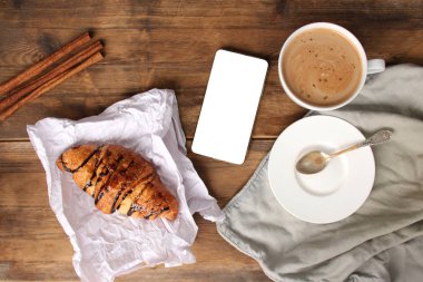 Çikolatalı kruvasan, beyaz ekranlı kapuçino akıllı telefon, kopyalama alanı, şablon