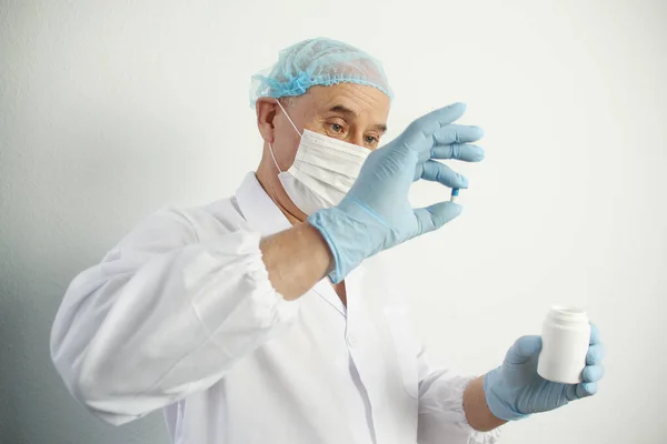 Forskare, äldre man, läkare, i en vit rock och en skyddsmask håller kapsel, begreppet farmakologiska, medicinska — Stockfoto