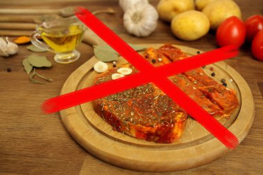Çiğ et, baharat turşulu iki et masanın üzerinde yuvarlak ahşap bir tahta üzerinde et madalyonu, sarımsak, patates, domates, soru işareti, vejetaryen, oruç günü konsepti, et reddi