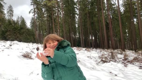 冬天穿着夹克的中年妇女在雪地的森林里鬼鬼祟祟 玩雪球 享受运动 健康的生活方式 — 图库视频影像